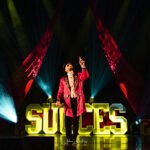 Artiste en costume rouge sur scène dans le spectacle Succès